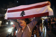 An anti-government protester chants slogans as she holds up a Lebanese flag joining others to block a road during a protest against the political leadership they blame for the economic and financial crisis, in Beirut, Lebanon, Thursday, June 11, 2020. (AP Photo / Hussein Malla)