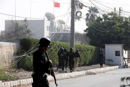 Police officers take cover as they move during an attack on the Chinese consulate, where blasts and shots are heard, in Karachi, Pakistan November 23, 2018. REUTERS/Akhtar Soomro