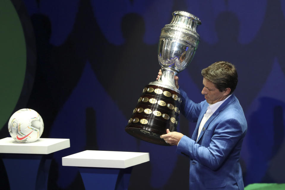 Brazilian former player Juninho Paulista places the Copa America trophy during the draw ceremony for the soccer tournament in Cartagena, Colombia, Tuesday, Dec. 3, 2019. The continental championship will be held in Colombia and Argentina from June 12 to July 12 next year. (AP Photo/Fernando Vergara)