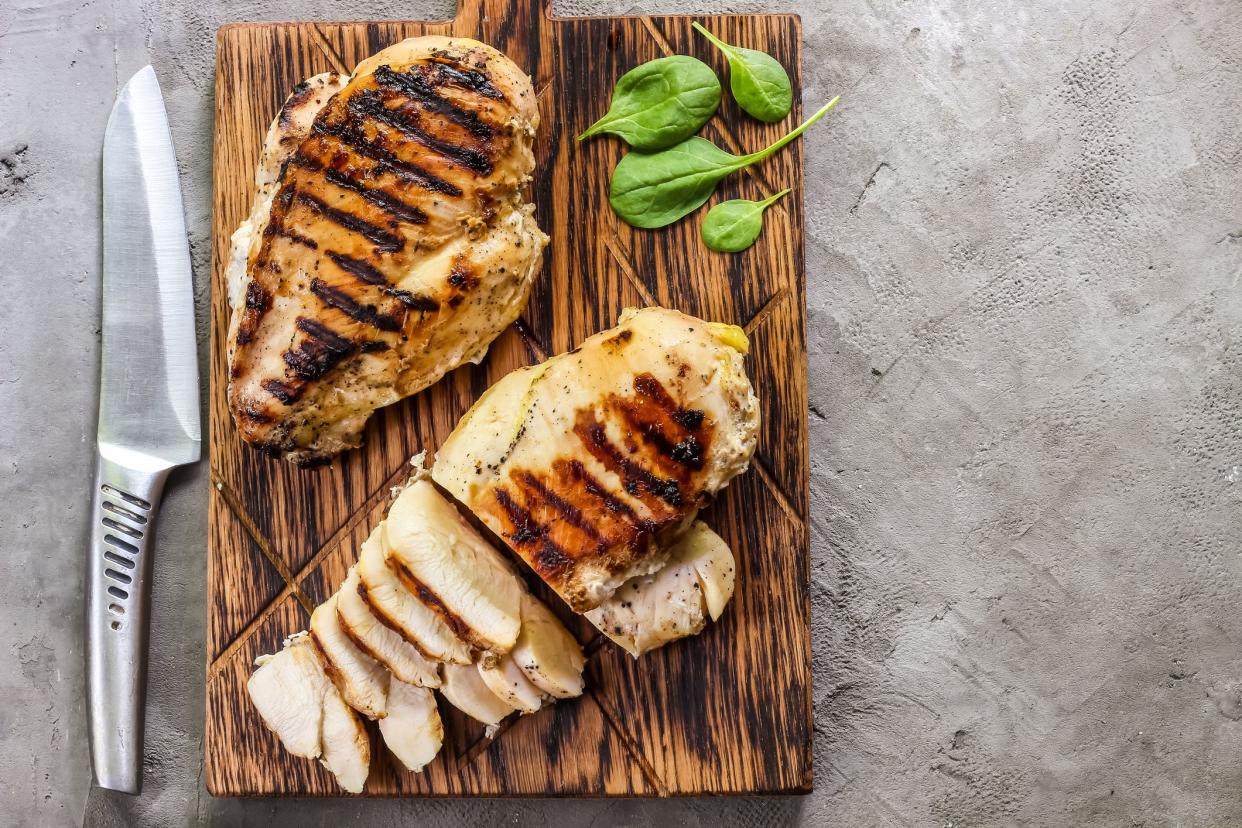 grilled chicken fillets on wooden cutting board prep with cooked quinoa and spinach for healthy food