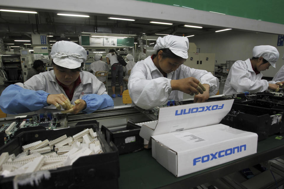 FILE - Staff members work on the production line at the Foxconn complex in the southern Chinese city of Shenzhen, southern China on May 26, 2010. Beijing's threats to use force to claim self-governed Taiwan aren't just about missiles and warships. Hard economic realities will be at play as voters head to the polls on Saturday, Jan. 13, 2024, though the relationship is complicated. (AP Photo/Kin Cheung, File)