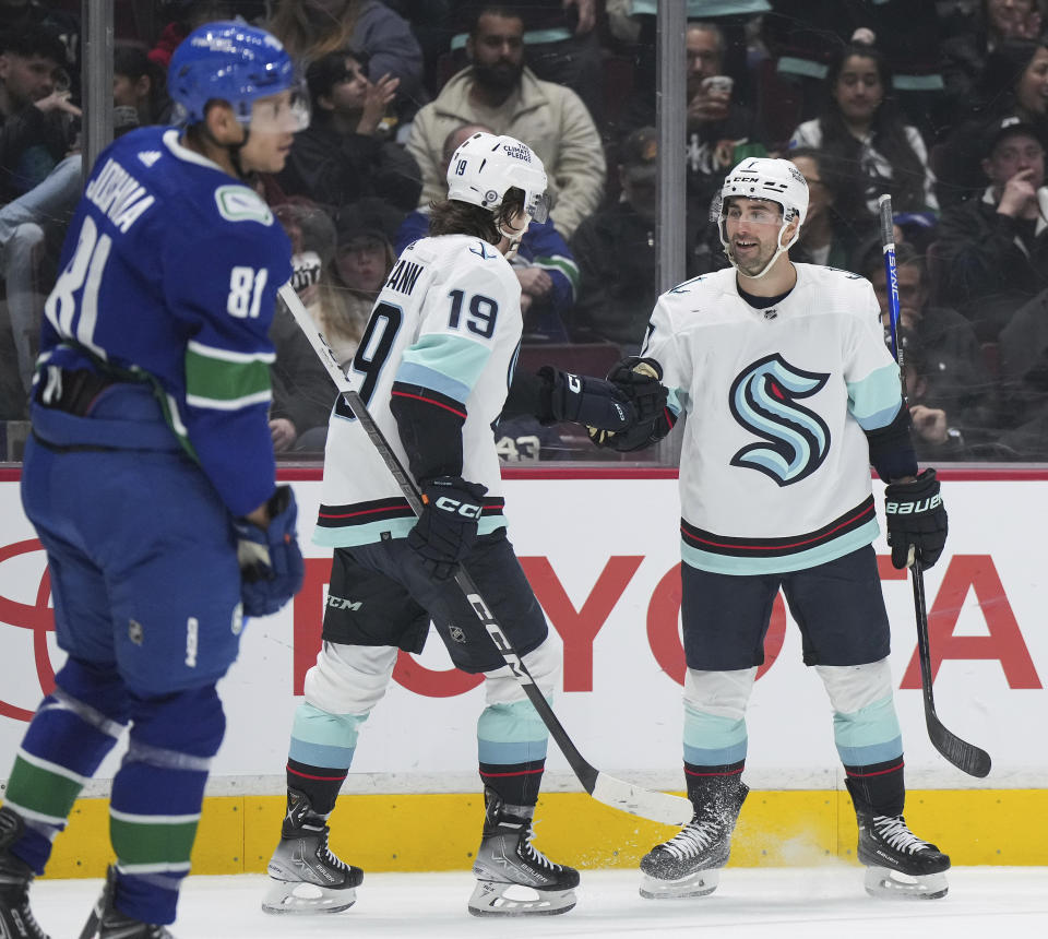 Seattle Kraken's Jordan Eberle, right, and Jared McCann celebrate Eberle's goal as Vancouver Canucks' Dakota Joshua (81) skates past during the second period of an NHL hockey game Tuesday, April 4, 2023, in Vancouver, British Columbia. (Darryl Dyck/The Canadian Press via AP)