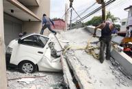 Workers use a crane to lift up concrete block that fell on a car after buildings collapsed during an earthquake in Cebu city, central Philippines October 15, 2013. REUTERS/Stringer