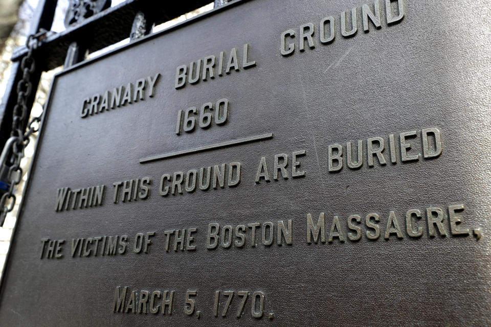 In this Tuesday, March 3, 2020 photo, a plaque is posted at the entrance to the Granary Burial Ground in Boston. The historic graveyard is the burial place of victims of the 1770 shooting by British soldiers, known as the Boston Massacre. The city is marking the 250th anniversary of the massacre that helped spark the Revolutionary War. The Daughters of the American Revolution is hosting a public tribute Thursday at the grave of the five victims of the violent conflict with British soldiers on March 5, 1770. (AP Photo/Steven Senne)