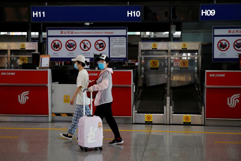 Women walk past check-in counters at Beijing Capital International Airport
