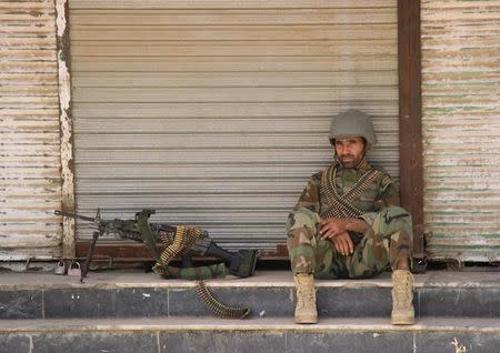 An Afghan National Army (ANA) soldier sits in front of a closed shop in the downtown of Kunduz city, Afghanistan October 3, 2016.REUTERS/Nasir Wakif