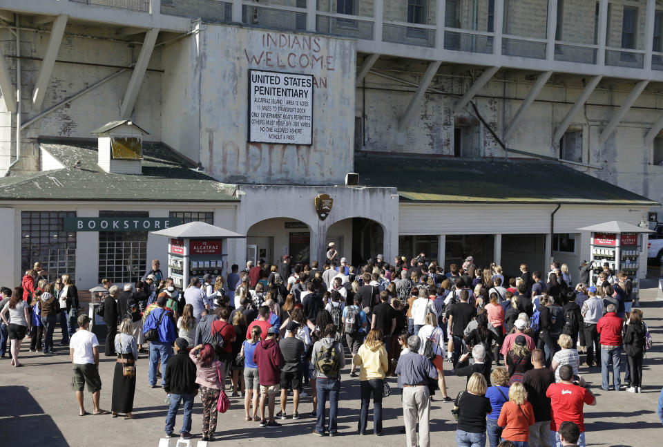 FILE - In this Oct. 17, 2013, file photo, a National Park Service ranger welcomes visitors to Alcatraz Island in San Francisco. Alcatraz Island will reopen its outdoor areas to the public next week after being closed for five months due to the pandemic. The Mercury News reports Thursday, Aug. 13, 2020, the island that once housed Al Capone and George "Machine Gun" Kelly will reopen Monday but will be an outdoor-only experience, to reduce the risk of spreading COVID-19. (AP Photo/Eric Risberg, File)