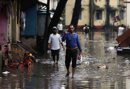 People walk through a partially flooded street at a residential area in Mumbai, India, August 30, 2017. REUTERS/Danish Siddiqui