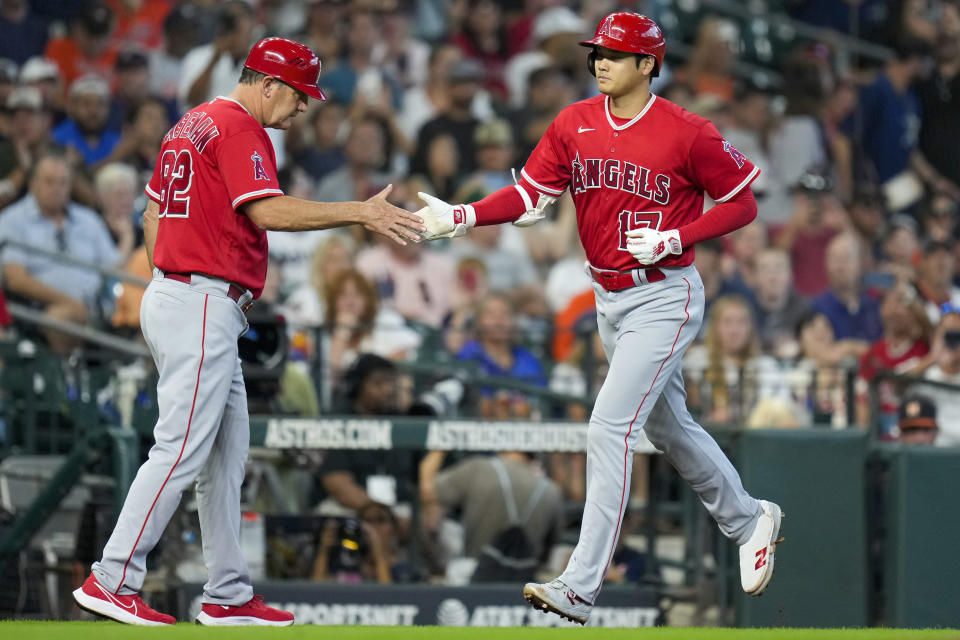 Los Angeles Angels designated hitter Shohei Ohtani, right, clasps hands with third base coach Bill Haselman after hitting a solo home run during the sixth inning of a baseball game against the Houston Astros, Sunday, Aug. 13, 2023, in Houston. (AP Photo/Eric Christian Smith)