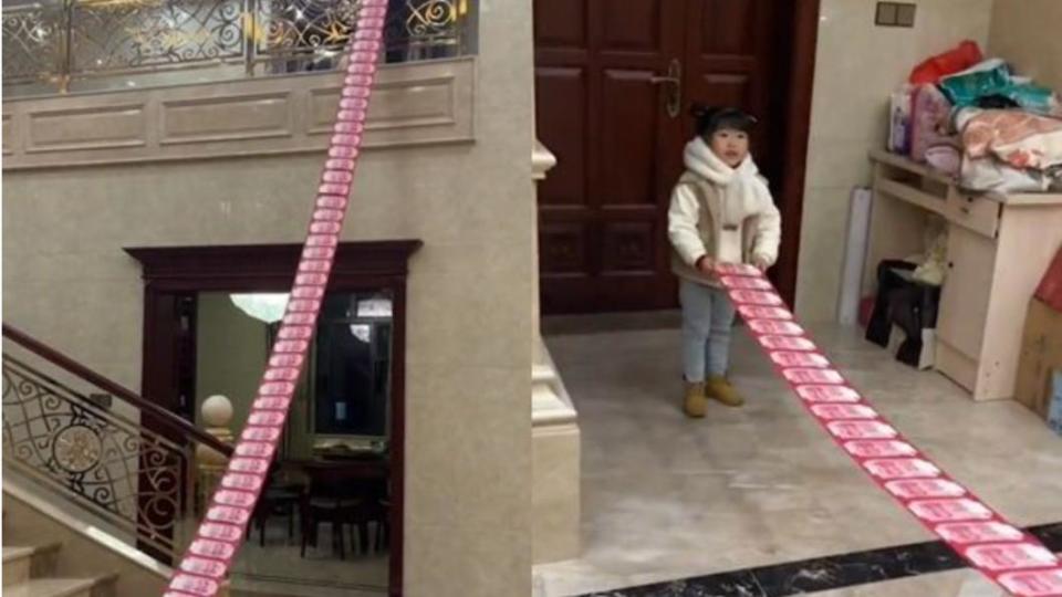 4歲女童拿著長達13公尺長的紅包。（圖／翻攝自《九派新聞》微博）