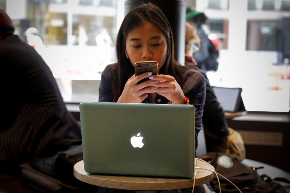 A woman uses her Apple iPhone and laptop in a cafe in lower Manhattan in New York City, U.S., May 8, 2019. REUTERS/Mike Segar