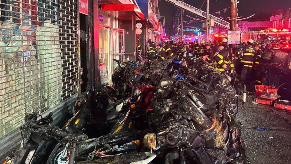 Several charred e-bikes and mopeds are seen outside a bike store in Queens after a battery exploded and burned down the store.