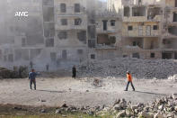 This photo provided by the anti-government activist group Aleppo Media Center (AMC), which has been authenticated based on its contents and other AP reporting, shows Syrian citizens passing in front of buildings that were damaged by Syrian government forces airstrikes, in Aleppo, Syria, Sunday April 20, 2014. (AP Photo/Aleppo Media Center, AMC)