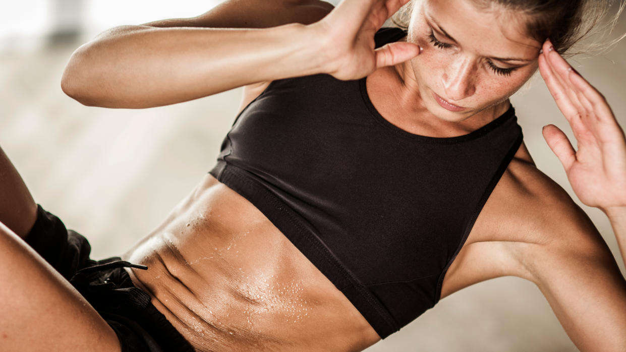  A woman doing a side crunch with her abs on show. 