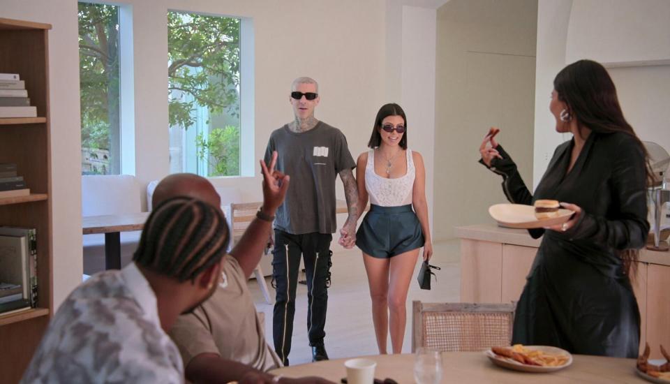 while the family is in the kitchen, Travis and Kourtney walk in holding hands