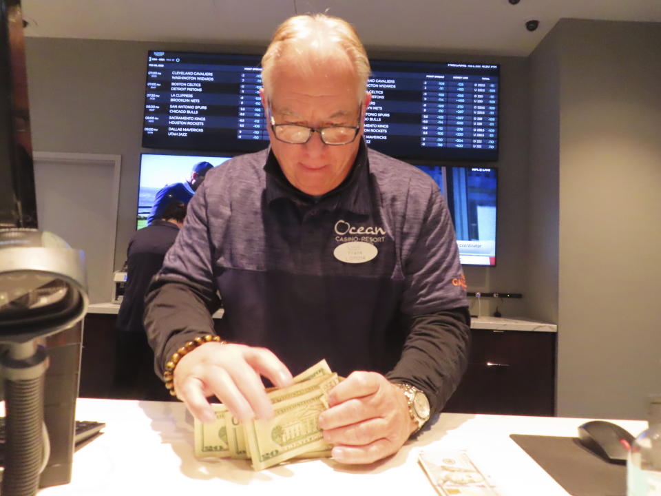 Frank Caltagirone, a sports book employee at the Ocean Casino Resort in Atlantic City N.J. counts money from his drawer on Feb. 6, 2023. Americans have bet over $220 billion on sports with legal gambling outlets in the five years since the U.S. Supreme Court cleared the way for all 50 states to offer it. (AP Photo/Wayne Parry)