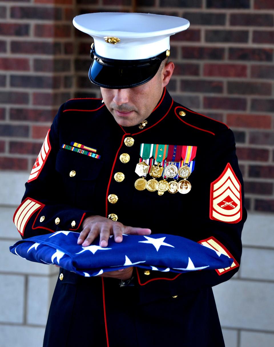 Gunnery Sgt. Josue Molina holds the flag which had covered the coffin of Herbert Alfred Lane, a 74-year-old Marine who died May 11.