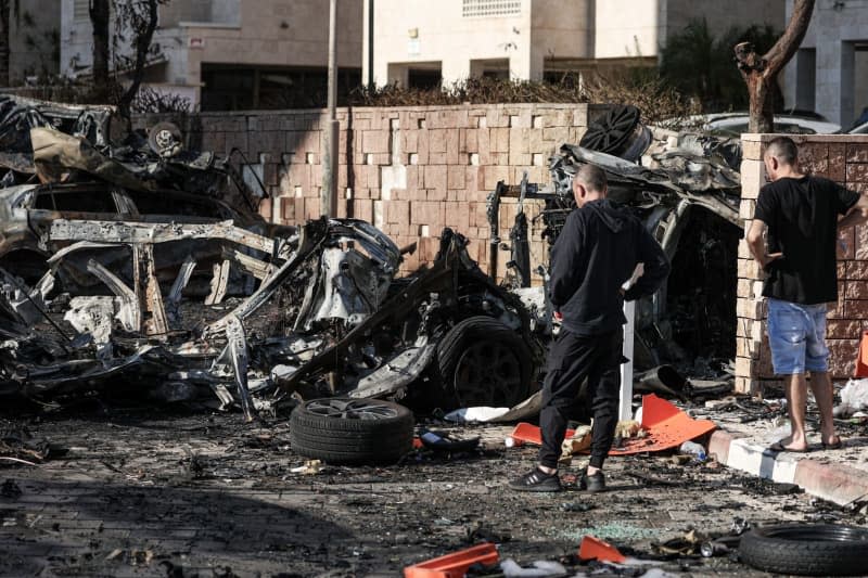 Residents look at the wreckage of destroyed vehicles following a rocket attack from Gaza. One member of the UN Relief and Works Agency (UNRWA) kidnapped an Israeli woman on October 7, another handed out ammunition and a third took part in the massacre of a kibbutz in which 97 people died, according to a report on Sunday in the New York Times (NYT). Ilia Yefimovich/dpa