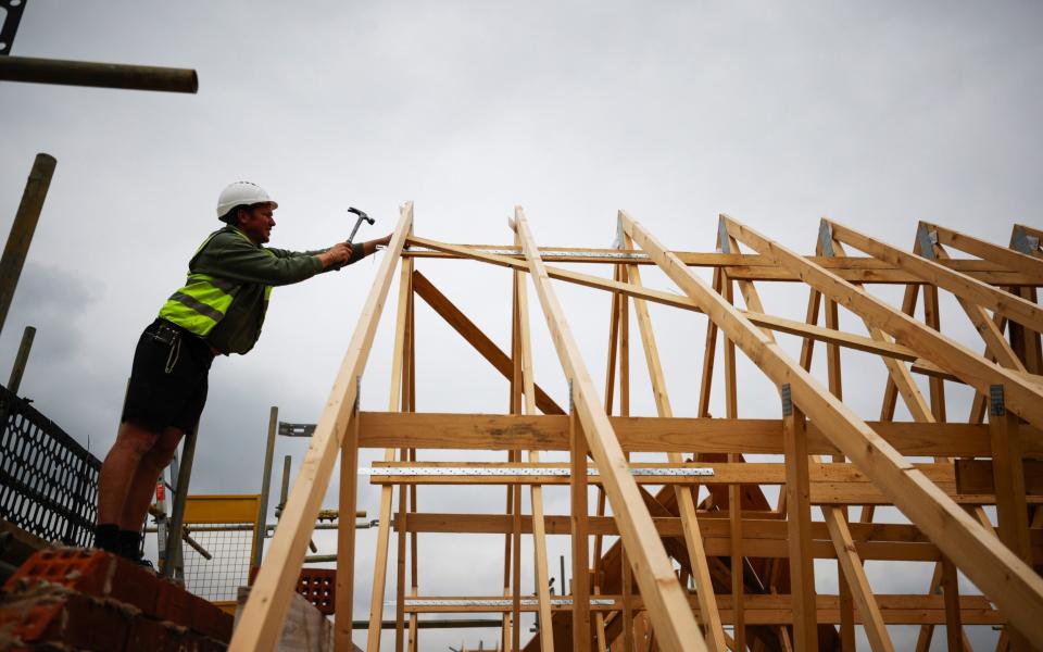 A worker secures trusses on a Persimmon residential property construction site in Chelmsford, 2021