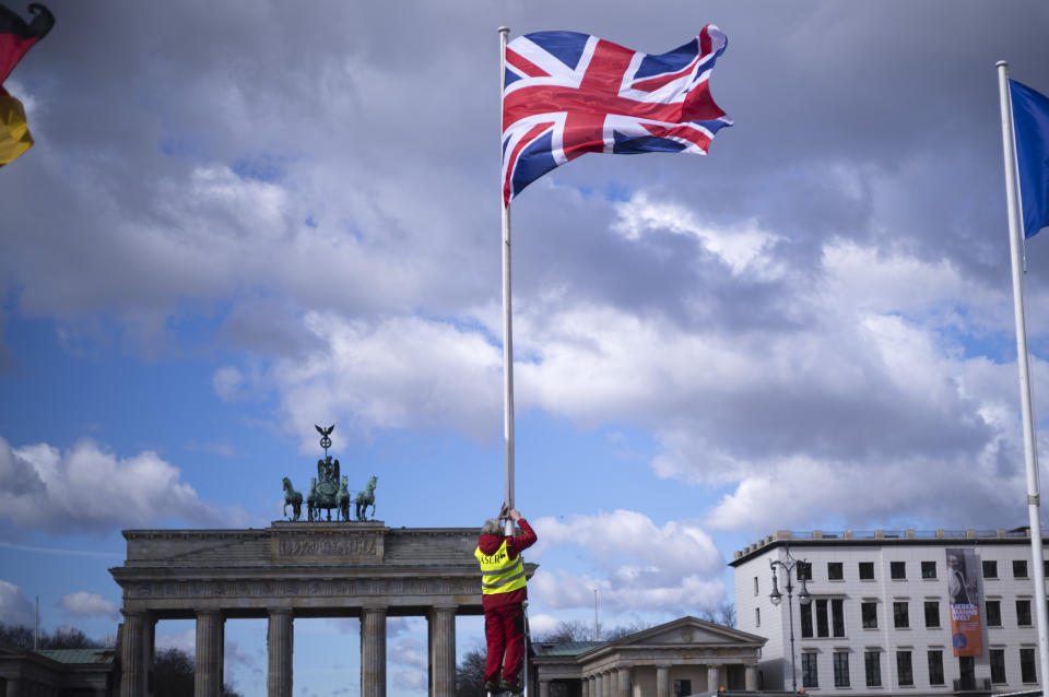 FILE - A person raises the Union Jack flag in front of the Brandenburg Gate at the eve of the visit of King Charles III at the German capital, in Berlin, Tuesday, March 28, 2023. King Charles III won plenty of hearts during his three-day visit to Germany, his first foreign trip since becoming king following the death of his mother, Elizabeth II, last year. (AP Photo/Markus Schreiber, File)