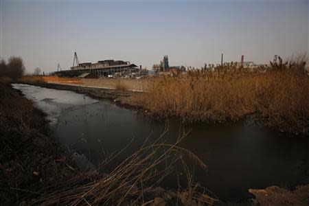 A partially frozen pond is pictured near an abandoned steel mill (back) of Qingquan Steel Group in Qianying township, Hebei province February 18, 2014. REUTERS/Petar Kujundzic