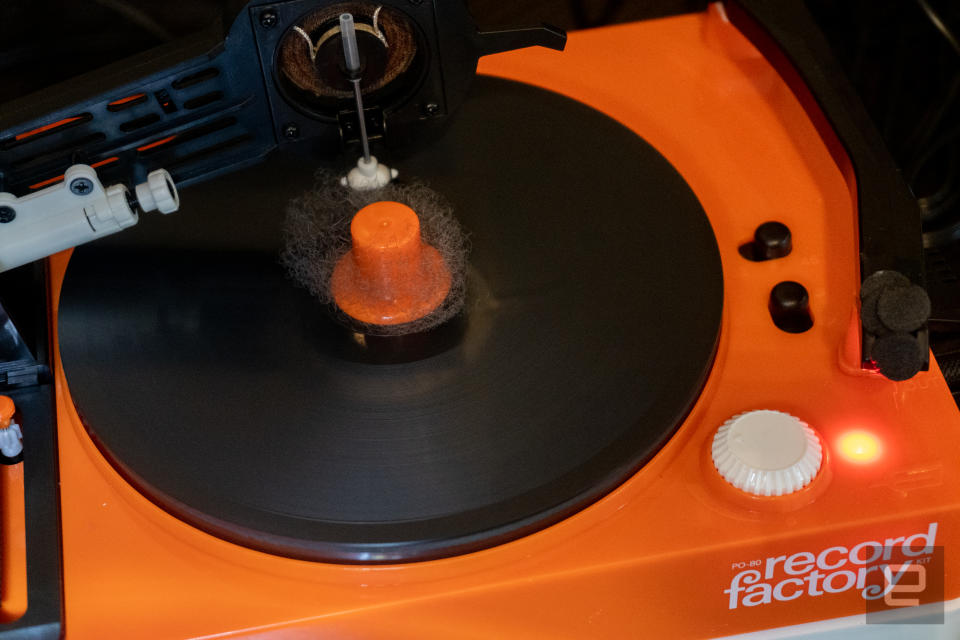 A closeup shot of an orange turntable  with some dust in its center, and the words 