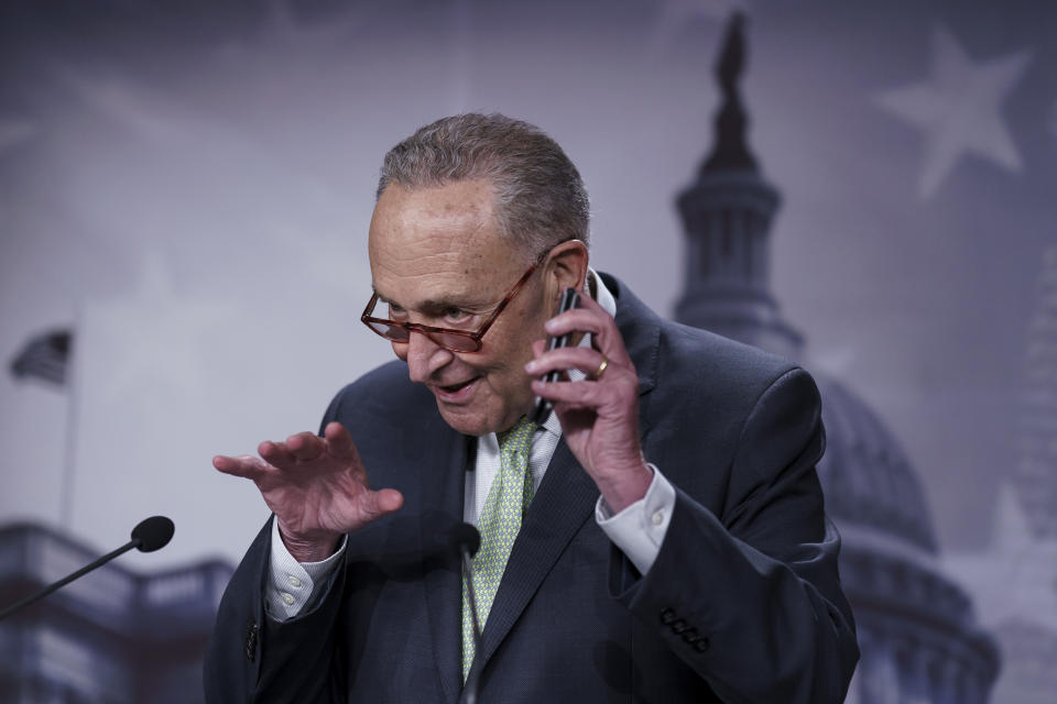 Sen. Chuck Schumer, clearly exultant, holds up his flip phone.