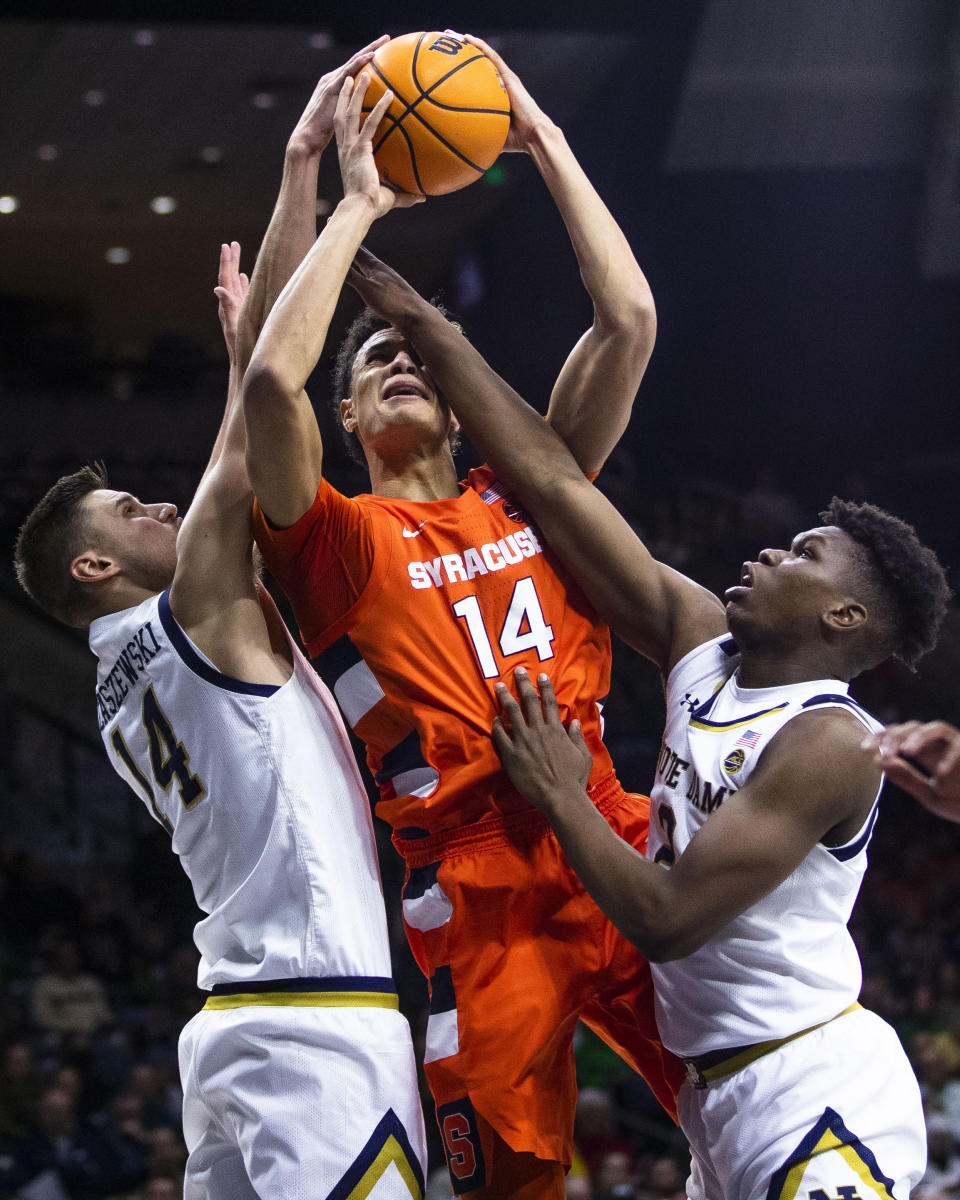 Syracuse's Jesse Edwards (14) tries to drive between Notre Dame's Nate Laszewski (14) and Trey Wertz, right, during the first half of an NCAA college basketball game on Saturday, Dec. 3, 2022 in South Bend, Ind. (AP Photo/Michael Caterina)