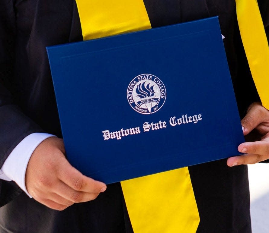A Daytona State College graduate holds a degree at a May 2023 commencement ceremony.