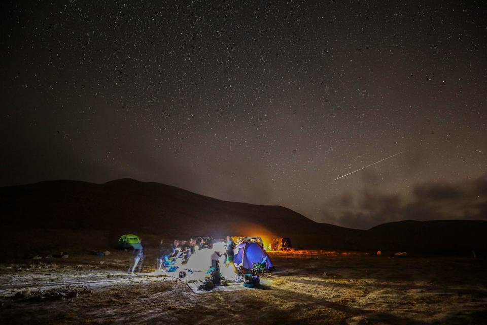 A Perseid meteor streaks across the sky above a camping site at the Negev desert near the city of Mitzpe Ramon, Israel on August 11, 2020.  / Credit: MENAHEM KAHANA/AFP via Getty Images