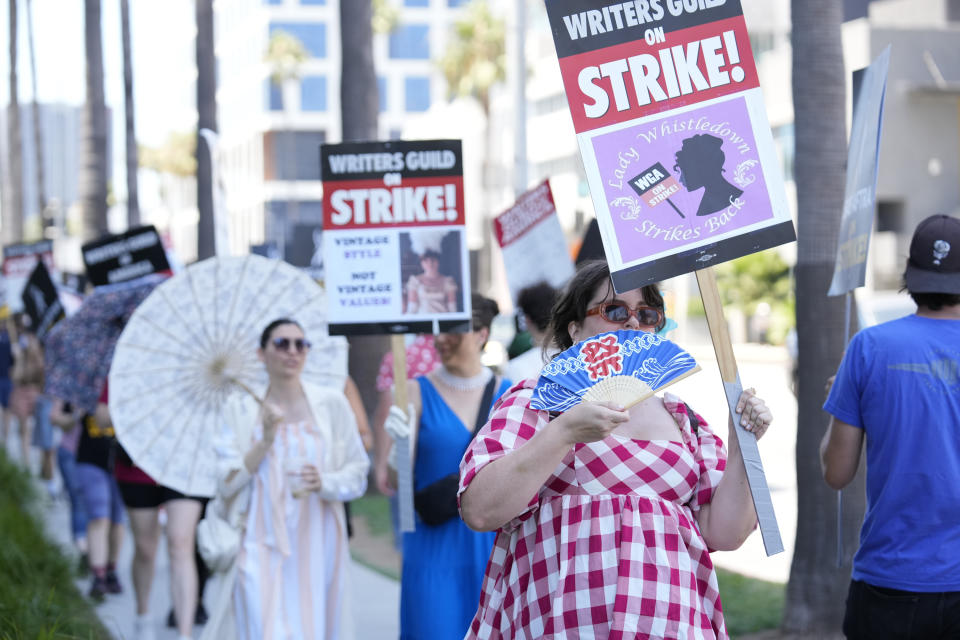 Picketers dressed as characters from "Bridgerton" carry signs outside Netflix studios on Tuesday, July 18, 2023, in Los Angeles. The actors strike comes more than two months after screenwriters began striking in their bid to get better pay and working conditions and have clear guidelines around the use of AI in film and television productions. (AP Photo/Chris Pizzello)