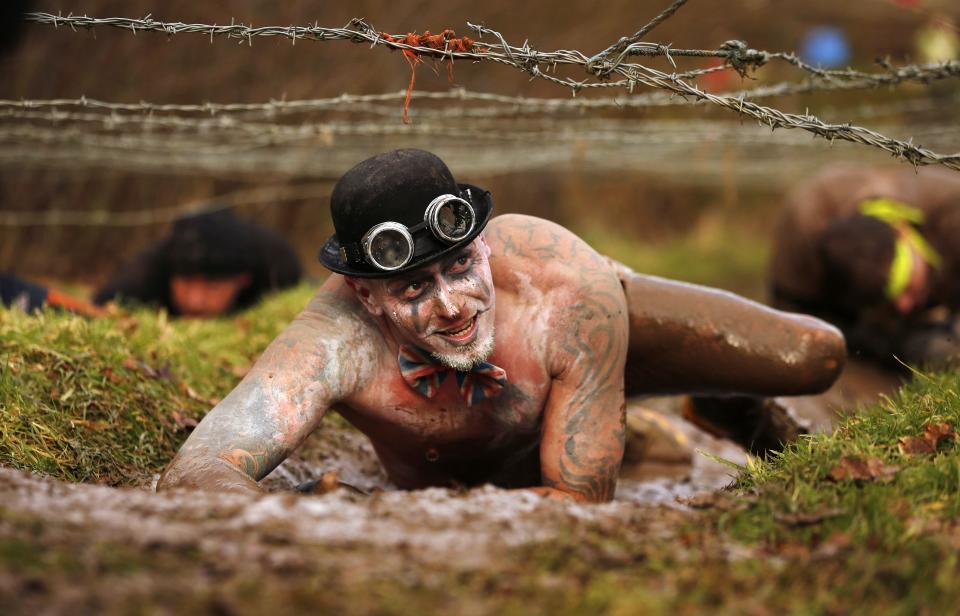 A competitor crawls beneath barbed wire during the Tough Guy event in Perton, central England