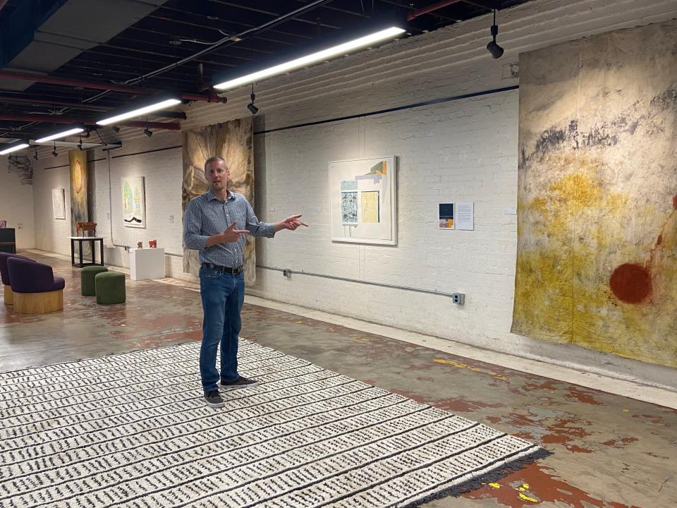 Matthew Bailey, university gallery director, points to a piece by professor and artist Jarrod Cluck.