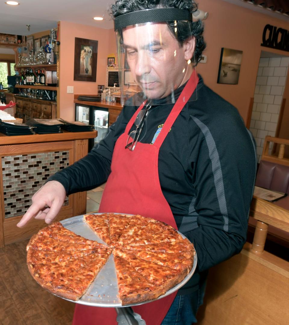 Owner Paul Bolanos prepares to serve a square of 'welcome' pizza at the Royal II Restaurant and Grill in Yarmouth Port in this file photo.