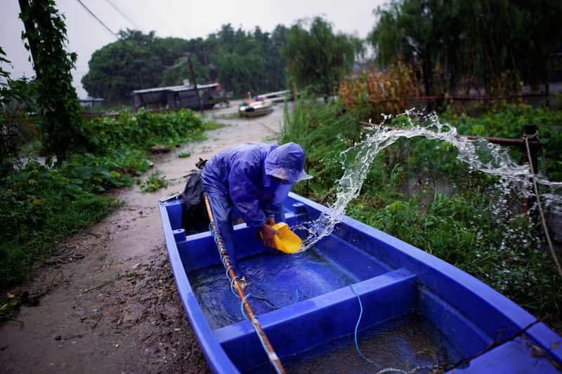 Man removes water from inside a boat near the Tai Lake, which has flooded its banks following heavy rainfall, in Huzhou