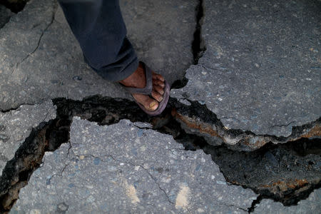 A man steps on a crack in a road at Balaroa neighbourhood hit by the earthquake and liquefaction in Palu, Central Sulawesi, Indonesia, October 10, 2018. REUTERS/Jorge Silva