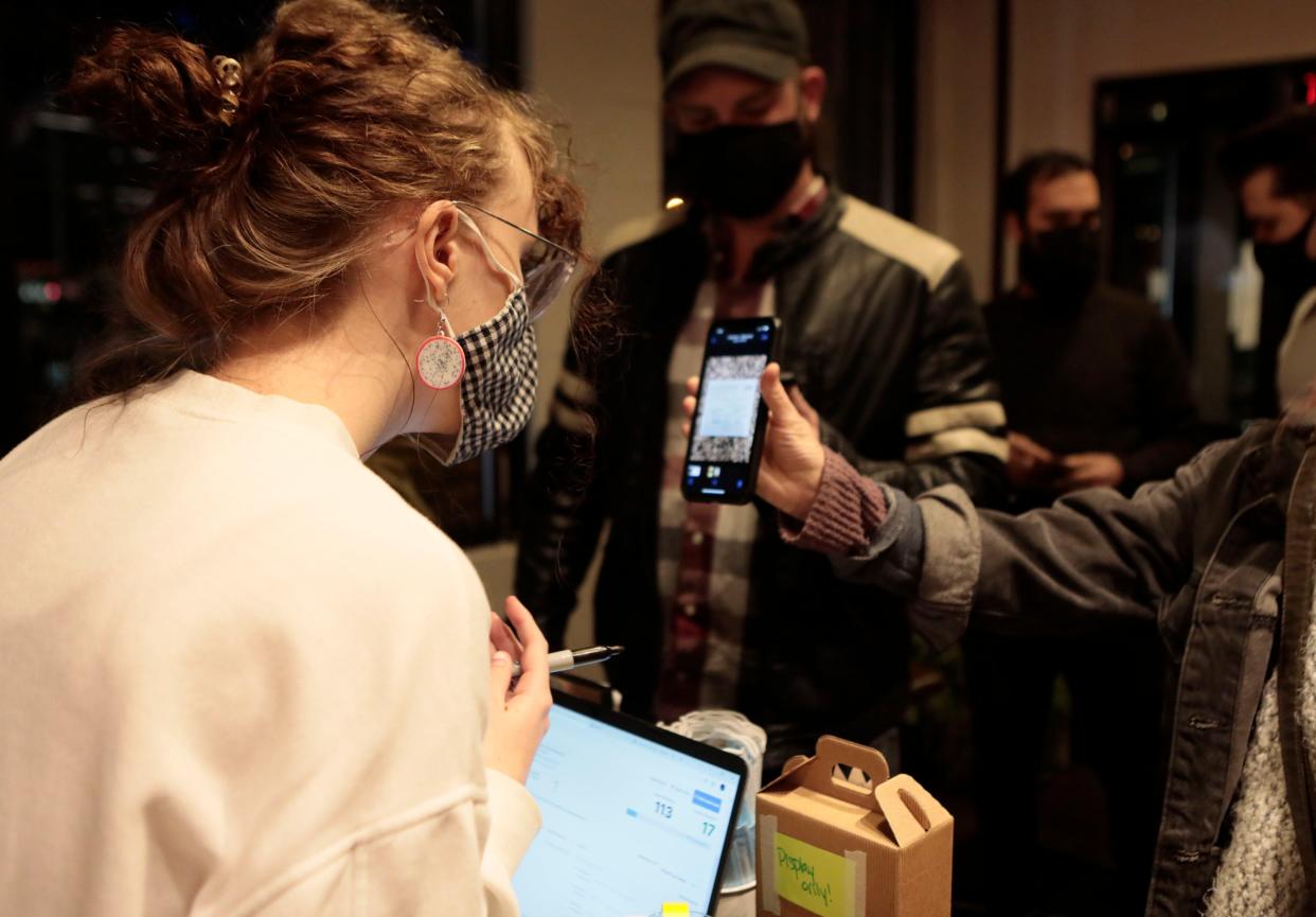 Hostess Melina Balch checks customers vaccination cards for entry at Natalie's Music Hall and Kitchen on King Avenue in Columbus, Ohio, on Friday, Dec. 3, 2021.