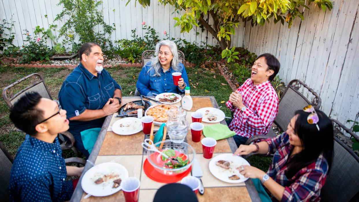 Diverse group of friends having dinner outdoors at a backyard bbq.