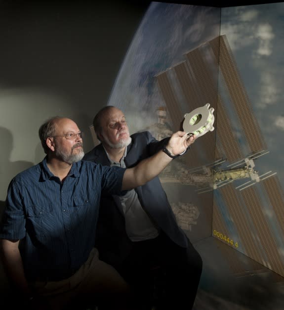 Goddard technologists Ted Swanson and Matthew Showalter hold a 3-D-printed battery-mounting plate developed specifically for a sounding-rocket mission. The component is the first additive-manufactured device Goddard has flown in space.