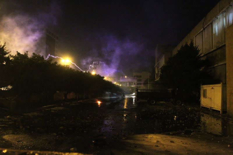 Smoke rises as stones are seen on the ground during a protest against the lockdown and worsening economic conditions, amid the spread of the coronavirus disease (COVID-19) at the government Serail building in Tripoli