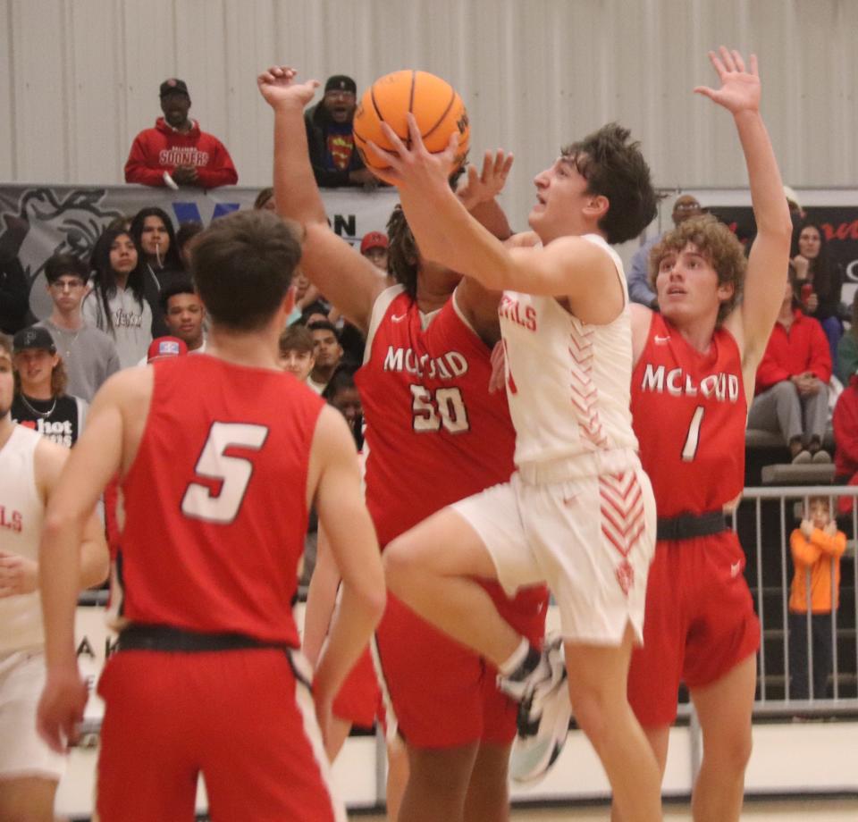 Prague's Blestin Miller goes up with the basketball among the defense of McLoud's Tryce Lewis (50) and Luke Jordan (1) Friday night in the semifinals of the 66 Conference Tournament in Meeker. McLoud's Coby Cardin (5) is in the foreground.