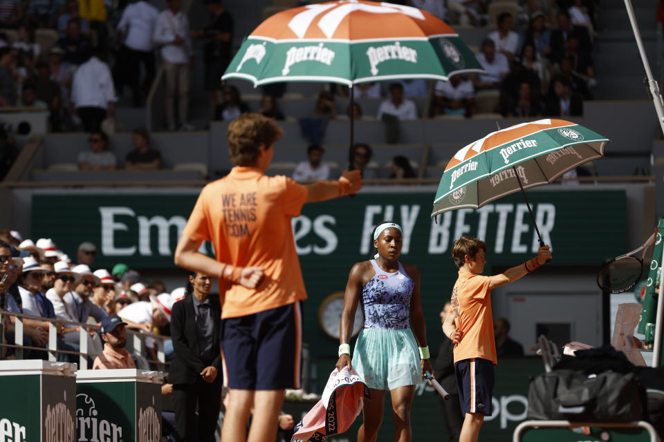 Ball boys carry umbrellas as Coco Gauff of the U.S.walks back to her bench while she plays Italy's Martina Trevisan during their semifinal match of the French Open tennis tournament at the Roland Garros stadium Thursday, June 2, 2022 in Paris. (AP Photo/Jean-Francois Badias)