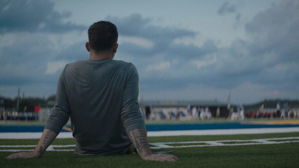 Johnny Manziel sits and looks out at his high school football field.