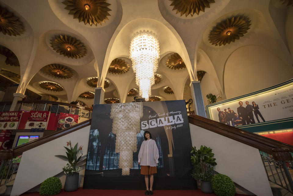 A woman poses for a souvenir photo at the lobby of the Scala theater Friday, July 3, 2020 in Bangkok, Thailand. The Scala theater has shut its doors after 51 years as a shrine for Thai movie-goers. (AP Photo/Sakchai Lalit)