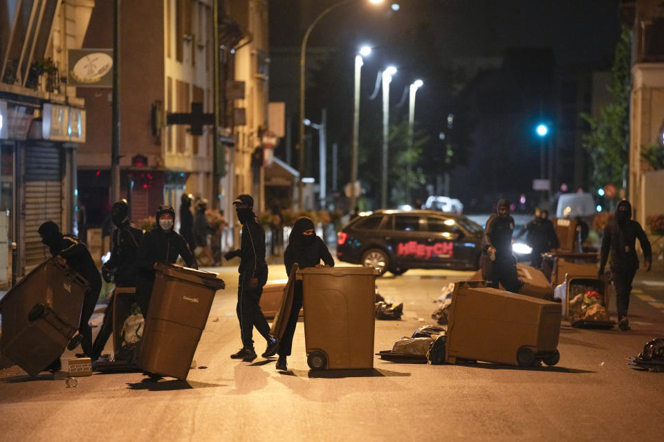 Protesters block a street with garbage cans in Colombes, outside Paris, France, Saturday, July 1, 2023. French President Emmanuel Macron urged parents Friday to keep teenagers at home and proposed restrictions on social media to quell rioting spreading across France over the fatal police shooting of a 17-year-old driver. (AP Photo/Lewis Joly)