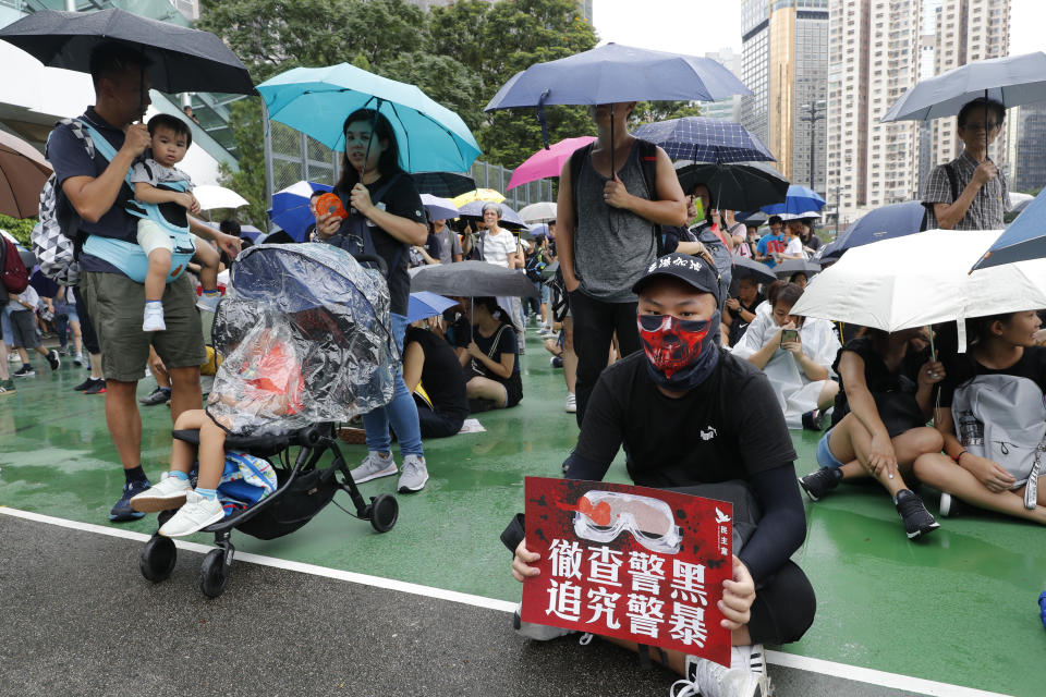 A protester holds up a card which reads "Thoroughly examine corrupt police, Investigate police brutality" during a rally in Hong Kong on Sunday, Aug. 18, 2019. A spokesman for China's ceremonial legislature condemned statements from U.S. lawmakers supportive of Hong Kong's pro-democracy movement, as more protests were planned Sunday following a day of dueling rallies that highlighted the political divide in the Chinese territory. (AP Photo/Vincent Thian)