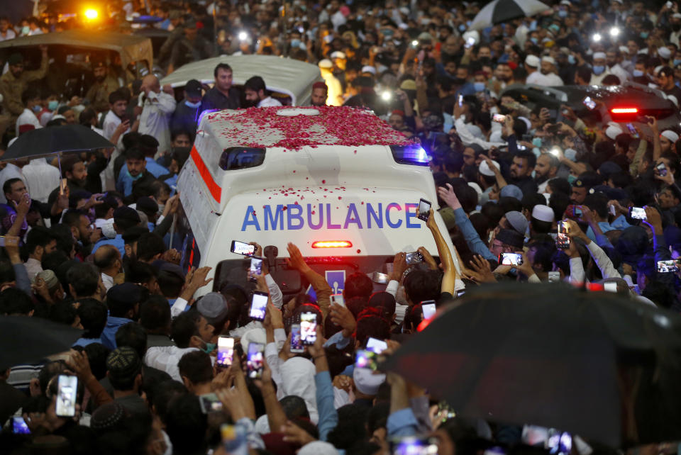 People move with an ambulance carrying the casket of Pakistani nuclear scientist Abdul Qadeer Khan following his funeral prayer, in Islamabad, Pakistan on Sunday, Oct. 10, 2021. Khan, a controversial figure known as the father of Pakistan's nuclear bomb, died Sunday of COVID-19 following a lengthy illness, his family said. He was 85. (AP Photo/Anjum Naveed)
