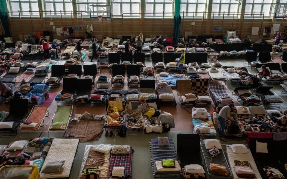 People who fled the war in Ukraine rest inside an indoor sports stadium being used as a refugee center, in the village of Medyka, a border crossing between Poland and Ukraine, on Tuesday, March 15, 2022. - AP Photo/Petros Giannakouris