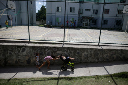 Luana Vieira, who is two years old, and was born with microcephaly, is pushed in a wheelchair by her sister Vitoria Evillen, near a sports court in the housing complex where they live, in Olinda, Brazil, August 6, 2018. REUTERS/Ueslei Marcelino/Files