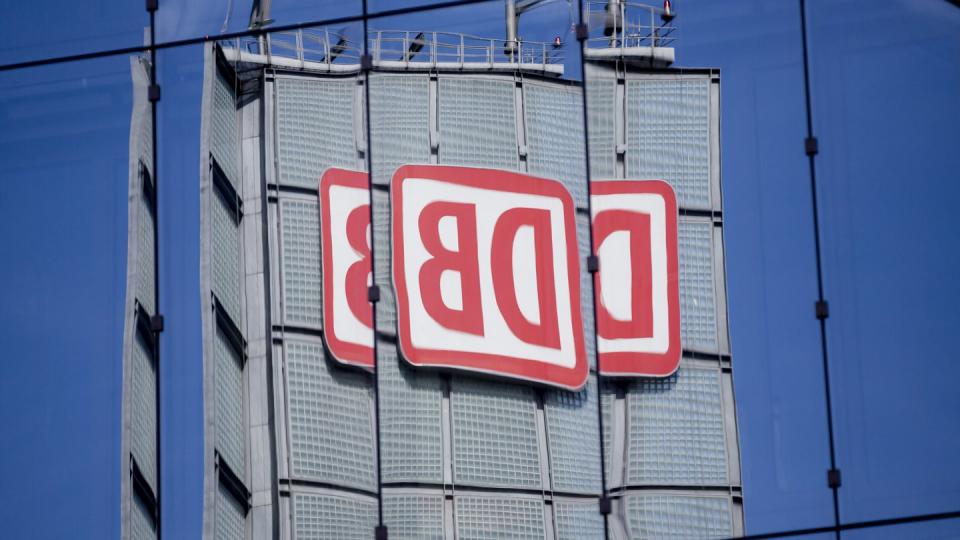 Das Logo der Deutschen Bahn AG spiegelt sich in Berlin in einer Gebäudefassade.